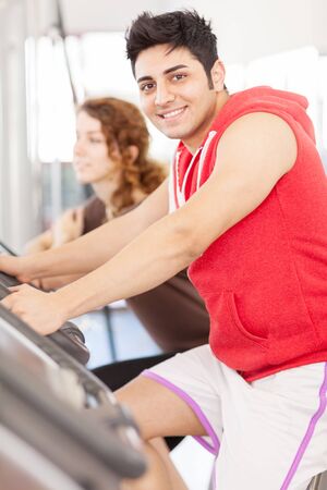 Photo of caucasian man looking at the camera while doing workout on the bicycle at the gymの写真素材