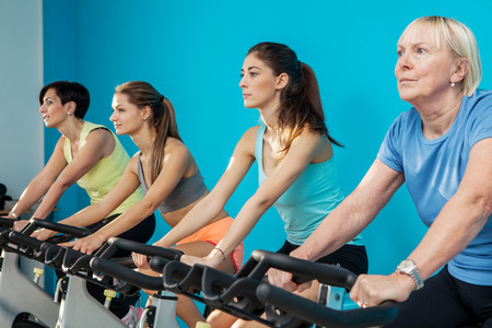 Photo of four women cycling at the fitness centerの写真素材