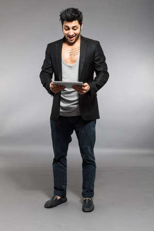 Caucasian man is standing with digital touch screen over grey backgroundの写真素材
