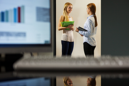Two businesswomen are discussing in the office corridorの写真素材