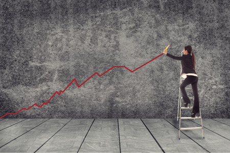 Asian businesswoman is drawing a red line while standing on theladderの写真素材