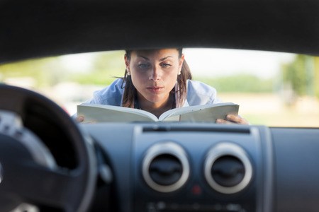 Caucasian businesswoman has a car problem and reads a car instructionの写真素材