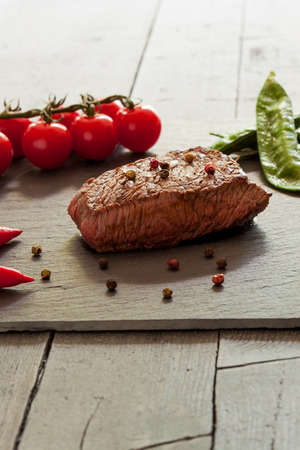 Delitious steak with vegetables over stone plateの写真素材