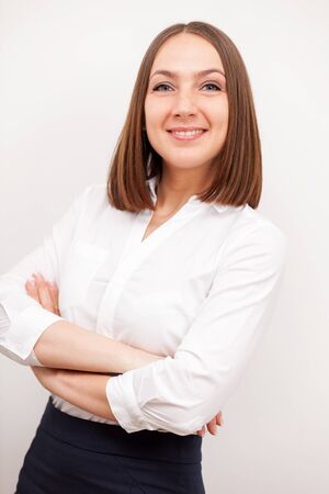 Portrait of successful brunette businesswoman with crossed hands over white isolated backgroundの写真素材