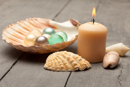 Photo of bath pearls in a shell over wooden tableの写真素材