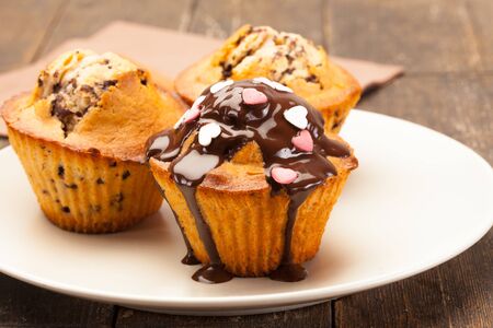 Photo of tasty cupcakes with chocolate over wooden tableの写真素材