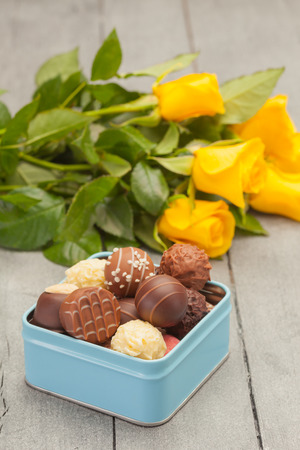 Photo of chocolate pralines with flowers over wooden tableの写真素材