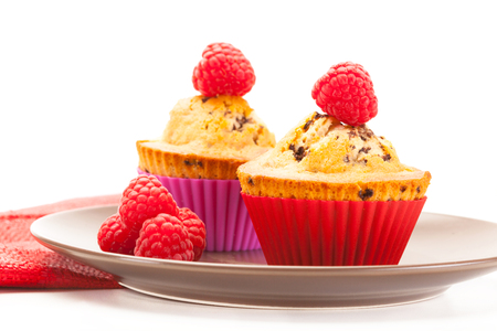 Photo of cupcakes with raspberries over white isolated backgroundの写真素材