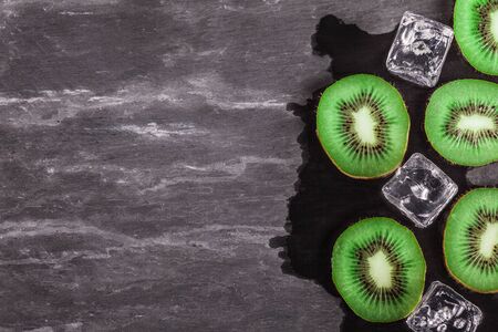 Top view of sliced kiwi and ice over stone tableの写真素材