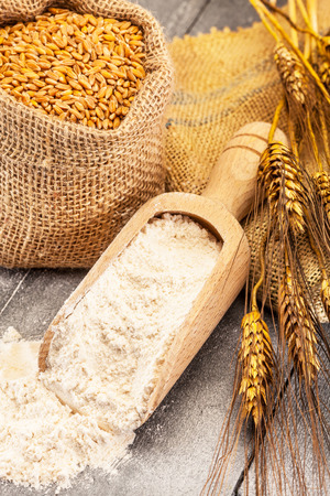 Photo of wheat grains and flour on the wooden tableの写真素材
