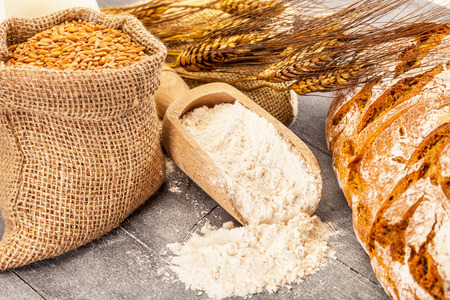 Photo of wheat grains and flour on the wooden tableの写真素材