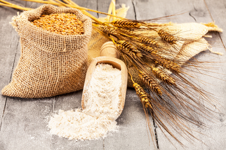 Photo of wheat grains and flour on the wooden tableの写真素材