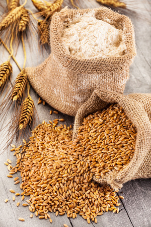 Photo of wheat grains and flour on the wooden tableの写真素材