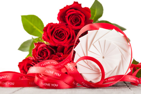 Photo of gift box and red roses over wooden tableの写真素材