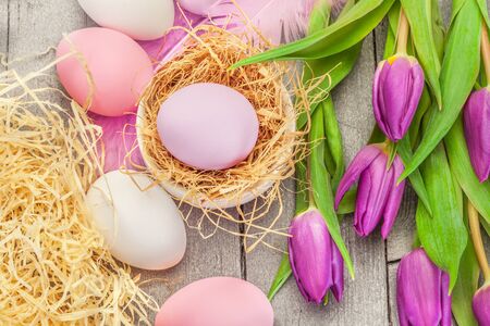 Top view of pink easter eggs and violet tulips over wooden tableの写真素材