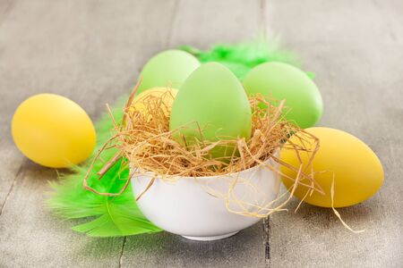Photo of easter eggs and feathers over wooden tableの写真素材