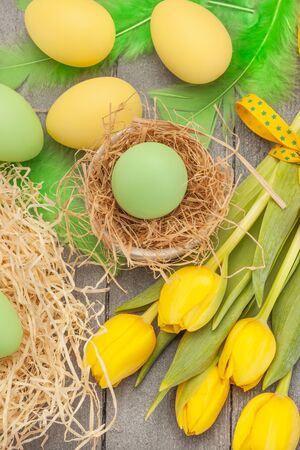 Top view of easter yellow tulips and eggs over wooden tableの写真素材