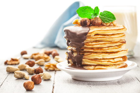 Photo of pancakes with chocolate and nuts over wooden tableの写真素材