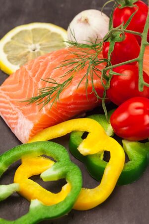 Photo of fresh tasty salmon with vegetables over black backgroundの写真素材