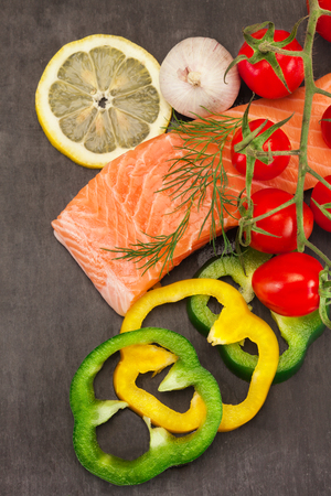 Photo of fresh tasty salmon with vegetables over black backgroundの写真素材