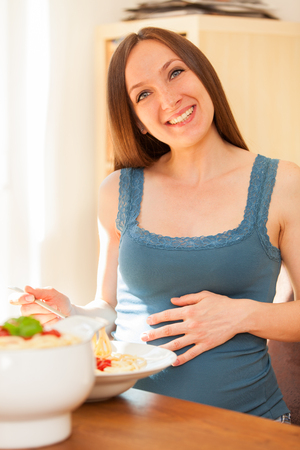 Photo of pregnant woman eating huge portion of pasta with tomato sauceの写真素材