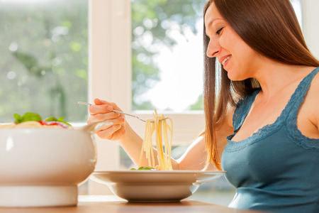 Photo of pregnant woman eating huge portion of pasta with tomato sauceの写真素材