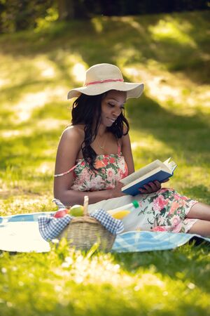 Attractive african woman is reading a book at picnicの写真素材