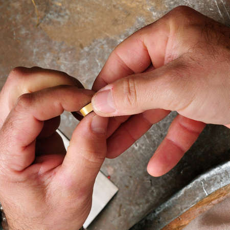 Skilled hands that create handmade jewelry with gold processing の写真素材