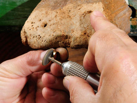 Skilled hands that create handmade jewelry with gold processing 