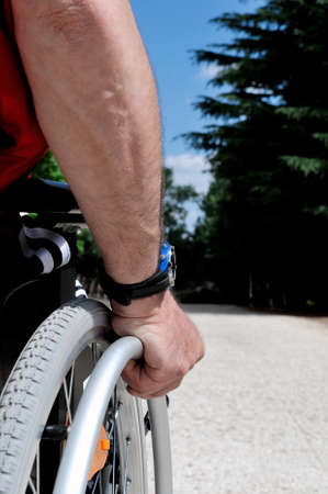 Hand of a man who runs her wheelchair in a country road.の写真素材