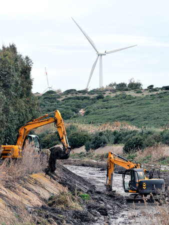 Large excavators engaged in cleaning of the riverbed of a river from the mud and debris.の写真素材