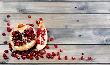 Closeup of ripe pomegranate fruit and seeds on an antique wooden baseの写真素材