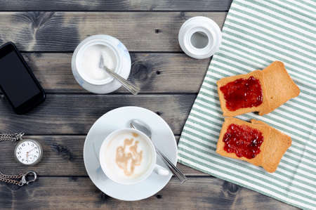 Foods of the Italian breakfast with coffee milk and rusks with jam on an old wooden tableの写真素材
