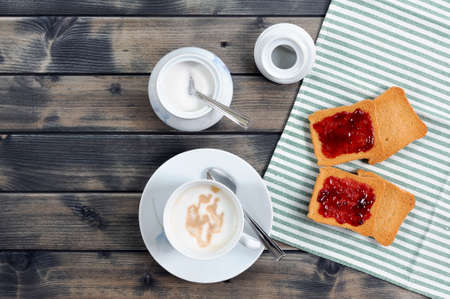 Foods of the Italian breakfast with coffee milk and rusks with jam on an old wooden tableの写真素材
