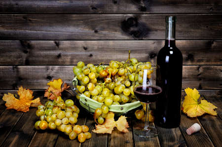 Glass of wine and fresh bunches of white grapes photographed on an old wood table.の写真素材