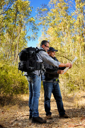 Hikers looking at the map on a forest trail on a beautiful autumn day