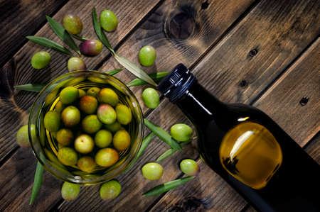 Shot from above of freshly harvested fresh olives and extra virgin olive oil on an aged wooden tableの写真素材