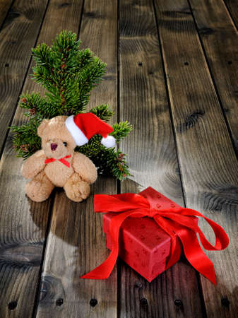 Close-up of a teddy bear and a Christmas box on an aged wooden table.の写真素材