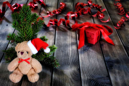 Close-up of a teddy bear and a Christmas box on an aged wooden table.の写真素材