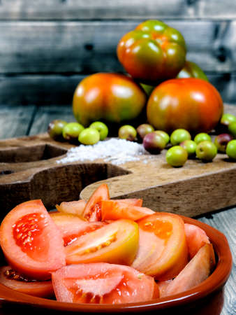 Close up of a bowl of tomato seasoned with olive oil on an old wooden tableの写真素材