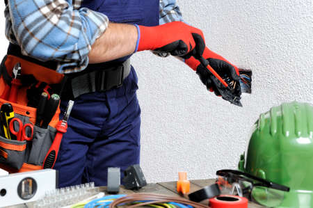 Electrician with hands protected by gloves and insulated tools works respecting the safety regulations in a residential electrical installation.の写真素材