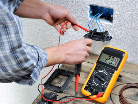 Young electrician at work measures the voltage of a residential electrical installation.の写真素材