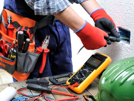 Young electrician technician operates on the electric cables of a residential facility.の写真素材