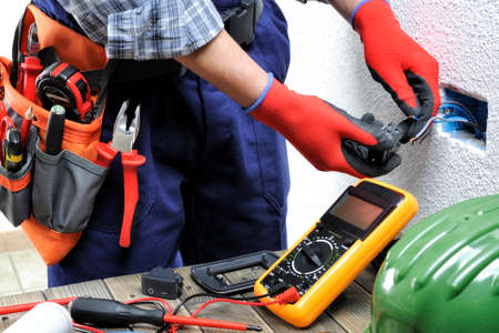 Young electrician technician at work on switches in a residential electrical installation.の写真素材