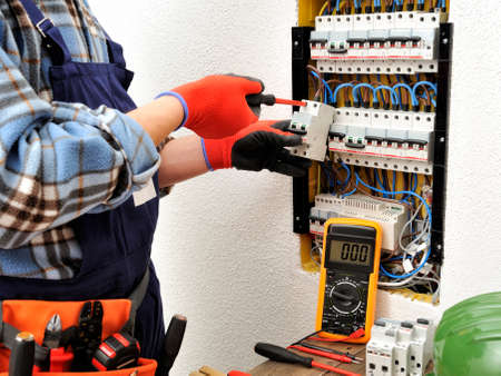 Young electrician technician fixes the electric cable to the magnetothermic switch with the screwdriverの写真素材