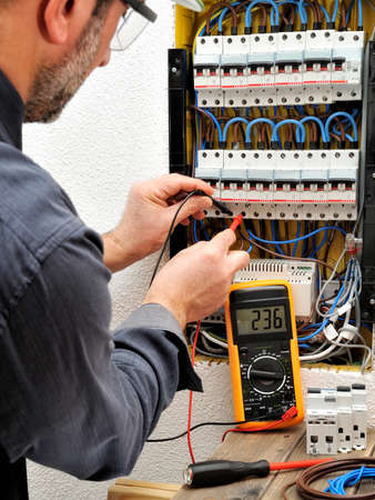 Technical electrician measures the voltage of a circuit breaker of a residential electrical panelの写真素材