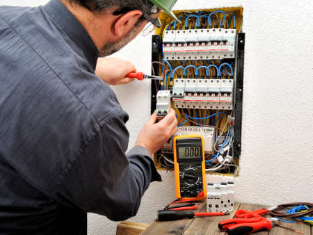 Electrician technician introduces the cable into the terminal of a magnetothermal switch of a residential electrical panelの写真素材