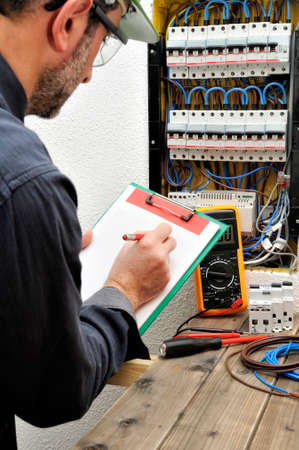 Electrical Technician writes in a notebook the data collected on a residential electric panelの写真素材