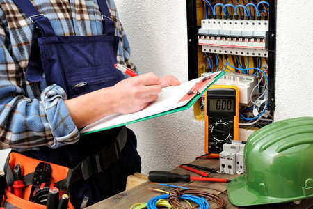 Young electrical technician writes in a notebook the data collected on a residential electric panelの写真素材