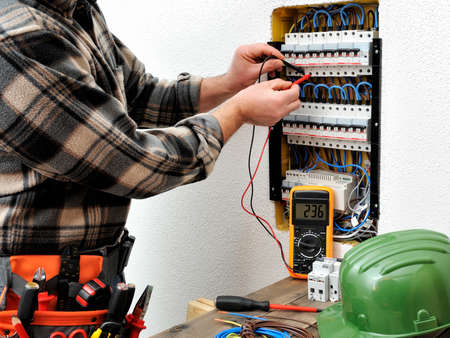 Technical electrician measures the voltage of a circuit breaker of a residential electrical panelの写真素材